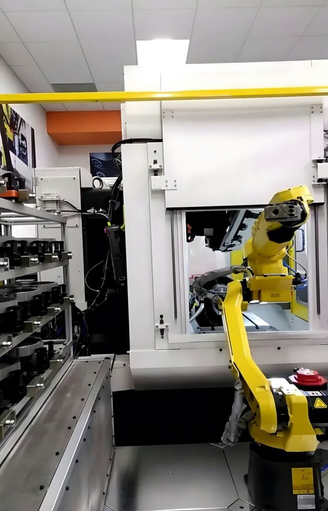 Yellow industrial robotic arm operating inside a manufacturing cell with precision equipment